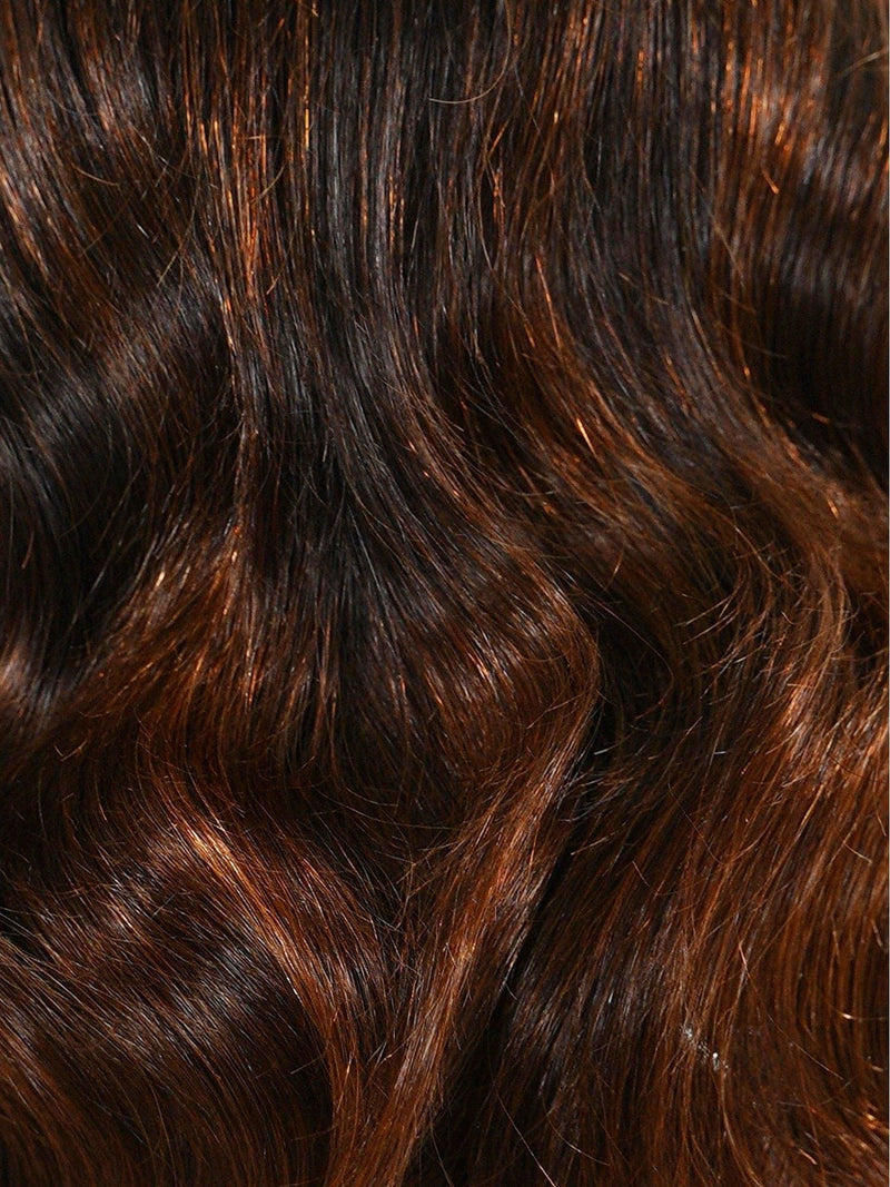 Dark brown hair with reddish highlights catches the light, emphasizing the natural waves, texture, and radiant shine of each strand.