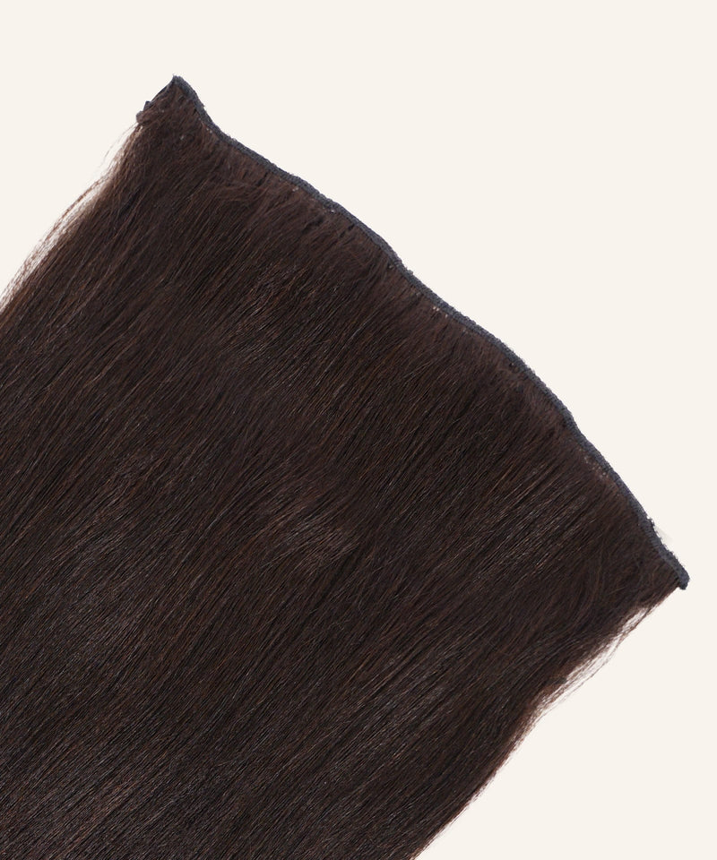 A close-up of Relaxed Straight Perfect Crown Hair Extensions in natural black by Perfect Locks against a light background.