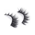 Dramatic black false eyelashes with thick, wispy, and curled fibers create a bold look, set against a clean white background.