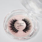 A pair of dramatic black false eyelashes in a round clear case with pink glittery background; label reads Perfect Lashes.