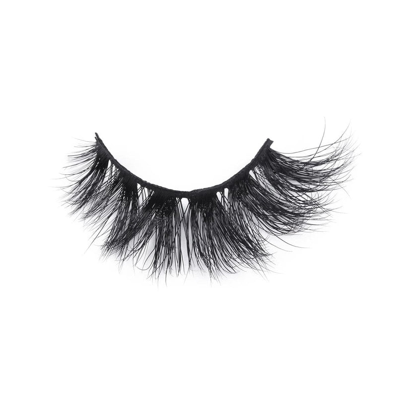 A single strip of dramatic, thick, black false eyelashes with long, wispy fibers creates a bold look on a white background.