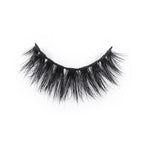 A single strip of dramatic, black, wispy false eyelashes curves in a semi-circle against a white background.