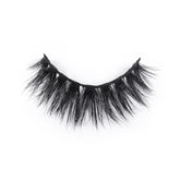 A single strip of dramatic, black, wispy false eyelashes curves in a semi-circle against a white background.