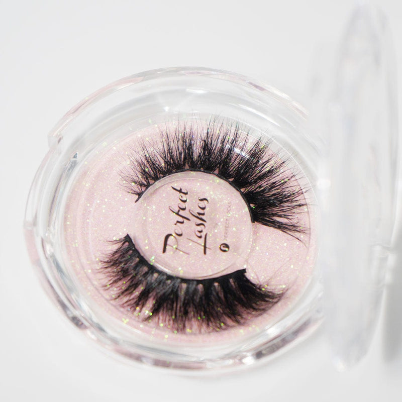 Dramatic, thick false eyelashes in a round clear case with a pink glittery background labeled Perfect Lashes add bold volume.