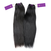 Two bundles of silky, straight dark hair extensions with purple tags rest side by side on a white background. The left bundle is slightly lighter in color than the right.