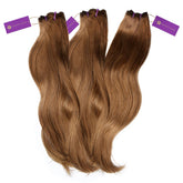Three bundles of long, wavy, light brown hair extensions laid side by side, each with a purple Perfect Locks tag at the top.
