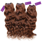 Three bundles of wavy, reddish-brown hair extensions with purple Perfect Locks tags are neatly arranged side by side for styling.
