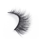 A single false eyelash with densely packed, long, wispy black fibers curves to fit the eyelid on a plain white background.
