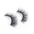 A pair of black, dramatic false eyelashes with a wispy, voluminous style offers a bold look, arranged on a white background.